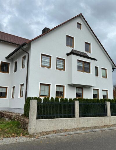 Frisch renovierte Hausfassade mit Silikonharzfarbe und farblich abgesetzten Fensterleibungen für klare Gliederung